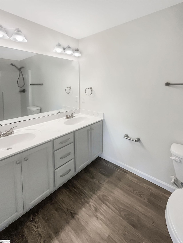 full bathroom featuring wood finished floors, a sink, toilet, and double vanity