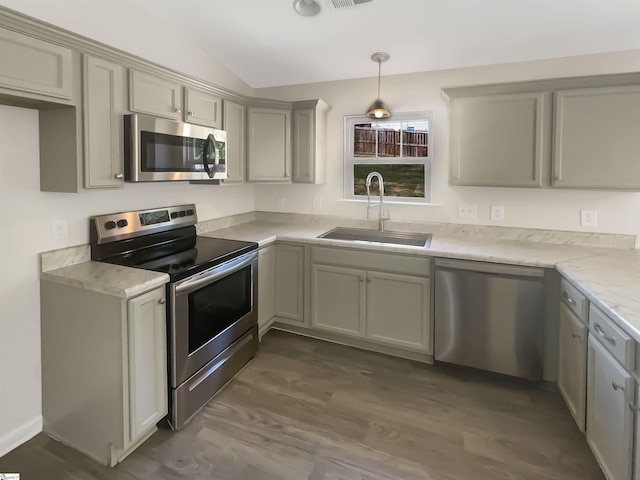 kitchen with stainless steel appliances, dark wood-style flooring, a sink, light stone countertops, and pendant lighting