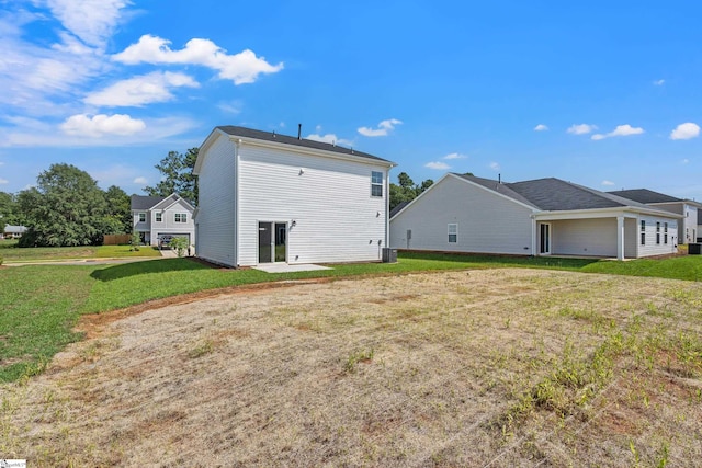 back of house with central AC unit and a lawn