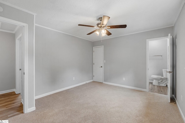 unfurnished bedroom featuring ensuite bath, a textured ceiling, ceiling fan, crown molding, and light carpet