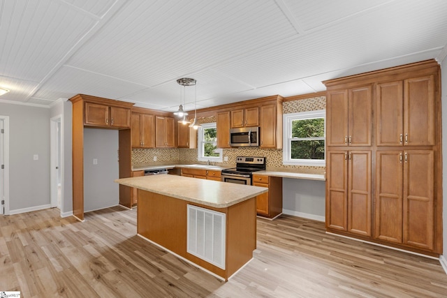 kitchen featuring decorative light fixtures, stainless steel appliances, a center island, and light hardwood / wood-style flooring