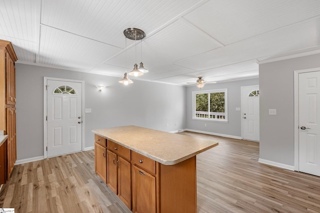 kitchen featuring hanging light fixtures, a center island, light hardwood / wood-style floors, and ornamental molding