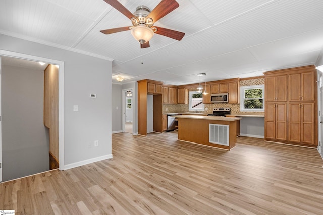 kitchen featuring light wood-type flooring, stainless steel appliances, decorative light fixtures, a kitchen island, and decorative backsplash