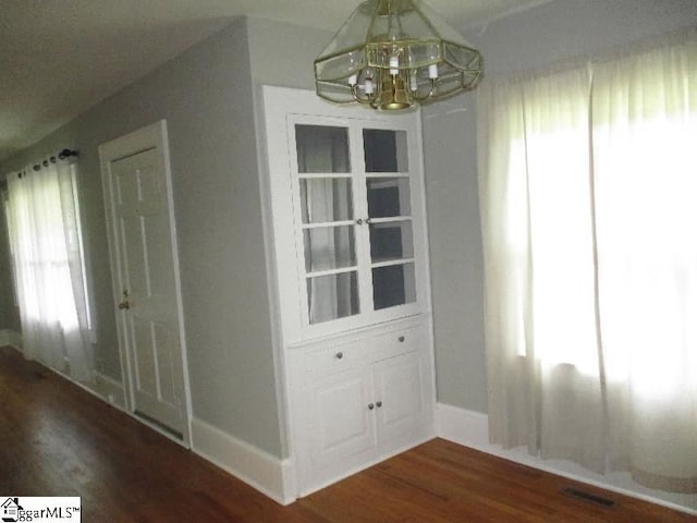 unfurnished dining area with a wealth of natural light, hardwood / wood-style flooring, and a notable chandelier