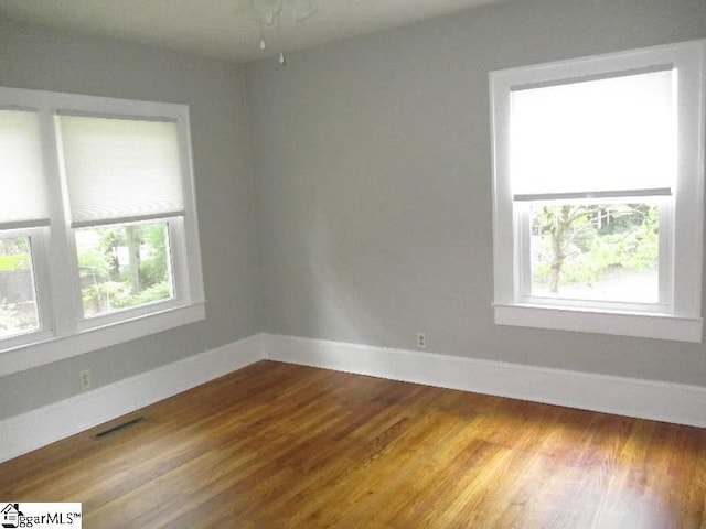 unfurnished room with hardwood / wood-style floors and plenty of natural light