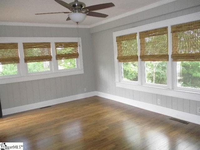 unfurnished room with a healthy amount of sunlight, ornamental molding, and hardwood / wood-style flooring