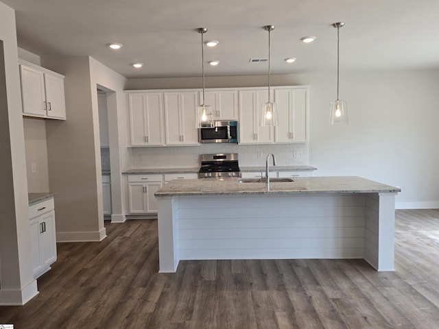 kitchen with decorative backsplash, white cabinetry, stainless steel appliances, and a sink