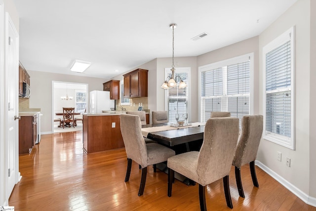 dining room featuring sink, light hardwood / wood-style floors, and an inviting chandelier