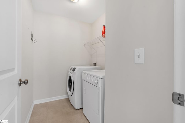 clothes washing area with washer and clothes dryer and light tile patterned floors