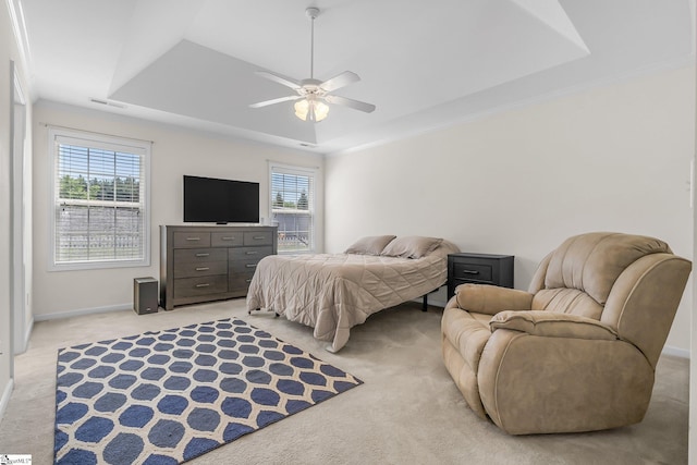 bedroom with ceiling fan, light carpet, and a tray ceiling