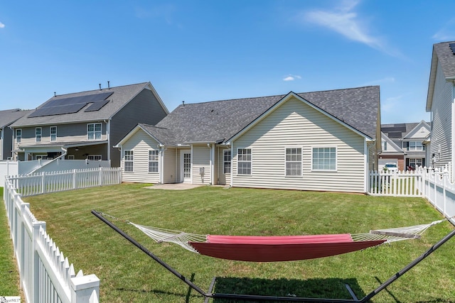 back of property with solar panels and a yard