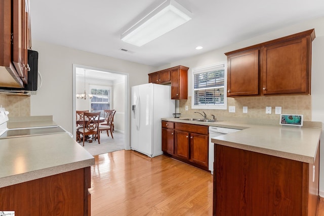 kitchen with a wealth of natural light, light hardwood / wood-style flooring, decorative backsplash, and white appliances