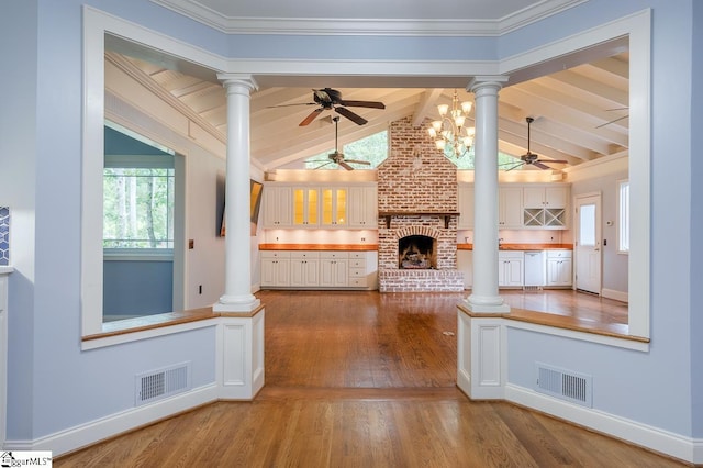 interior space featuring white cabinetry, decorative columns, a brick fireplace, and visible vents