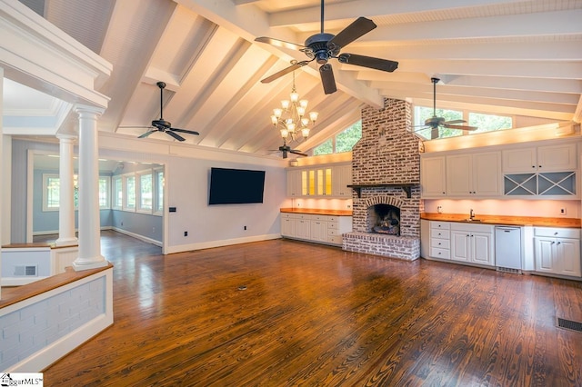 unfurnished living room with a brick fireplace, decorative columns, beam ceiling, and dark wood-type flooring