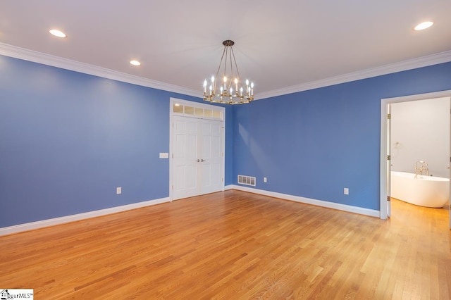 empty room featuring light wood finished floors, ornamental molding, visible vents, and baseboards