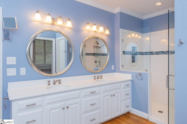 full bathroom featuring wood finished floors, a sink, double vanity, a stall shower, and crown molding