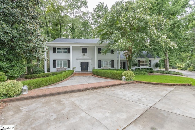 neoclassical / greek revival house featuring a front lawn and stucco siding