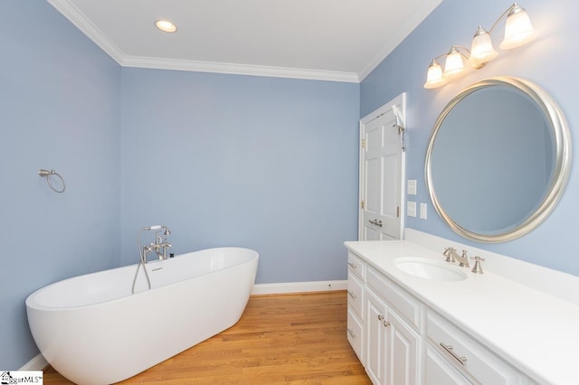 bathroom featuring baseboards, ornamental molding, wood finished floors, and vanity