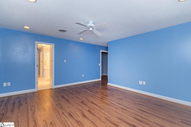 spare room with visible vents, a ceiling fan, a textured ceiling, wood finished floors, and baseboards