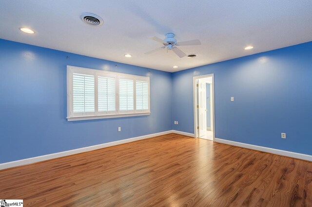 spare room with visible vents, ceiling fan, baseboards, and wood finished floors