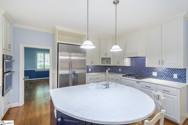 kitchen featuring stainless steel appliances, tasteful backsplash, custom range hood, white cabinetry, and a sink