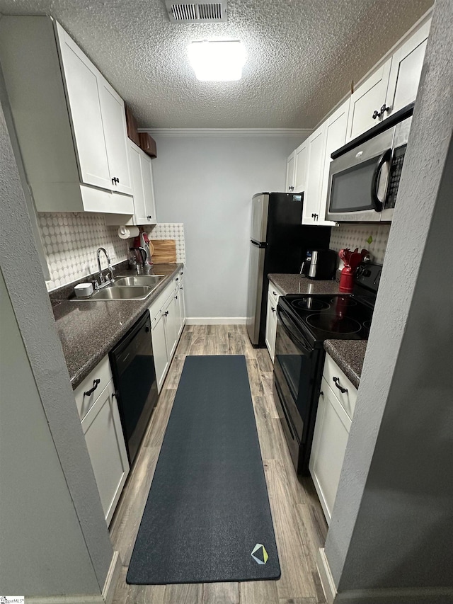 kitchen with light wood-type flooring, black appliances, backsplash, and sink