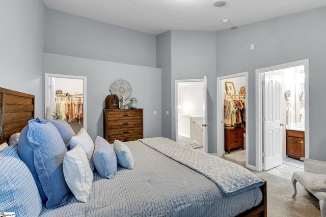 carpeted bedroom with a walk in closet, a closet, a towering ceiling, and ensuite bathroom