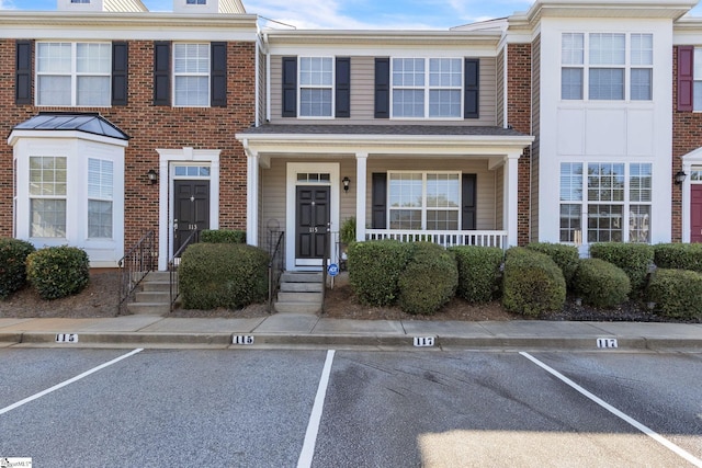 townhome / multi-family property with uncovered parking and brick siding