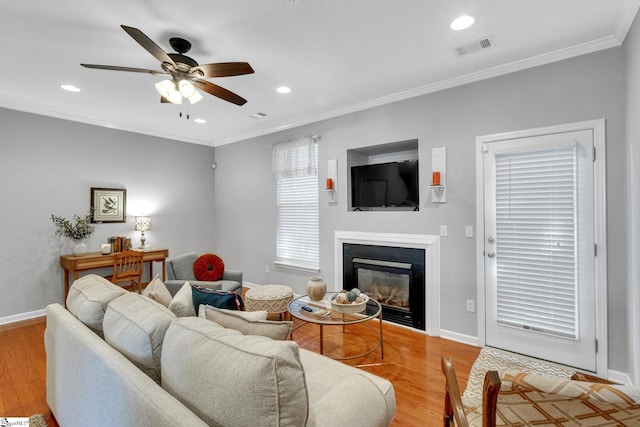 living room featuring ceiling fan, light wood-type flooring, and crown molding