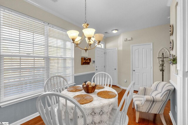 dining room with plenty of natural light, a notable chandelier, crown molding, and hardwood / wood-style flooring