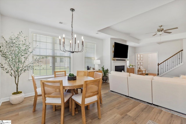 dining space featuring ceiling fan with notable chandelier and light hardwood / wood-style flooring