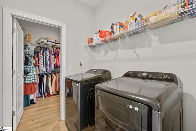 laundry room with a chandelier, light hardwood / wood-style floors, and washer and clothes dryer