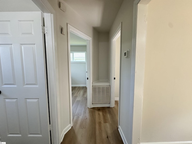 hallway with visible vents, baseboards, and wood finished floors