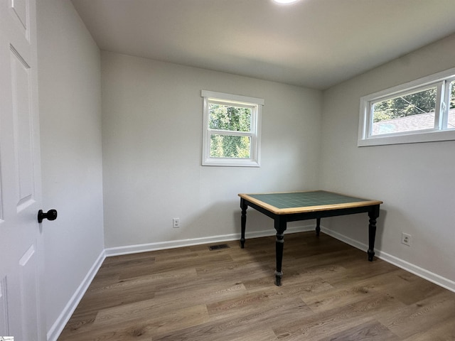 unfurnished office with baseboards, wood finished floors, visible vents, and a healthy amount of sunlight