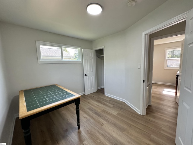 unfurnished bedroom featuring light wood-type flooring, a closet, and baseboards