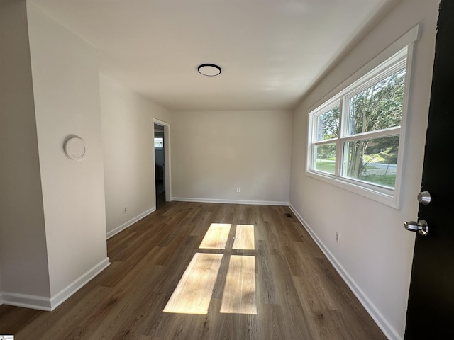 unfurnished room featuring dark wood-style flooring and baseboards