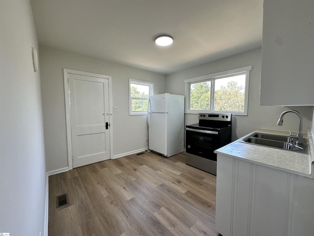 kitchen with a sink, visible vents, light countertops, stainless steel electric range, and freestanding refrigerator