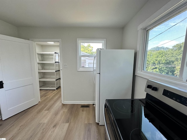 kitchen featuring electric range, visible vents, baseboards, freestanding refrigerator, and light wood-style floors