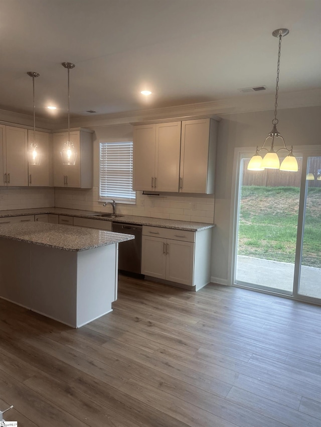 kitchen with light hardwood / wood-style flooring, pendant lighting, dishwashing machine, light stone countertops, and sink