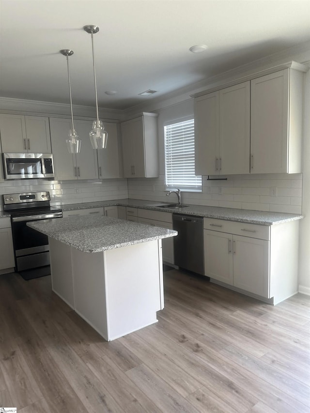 kitchen with appliances with stainless steel finishes, backsplash, light wood-type flooring, pendant lighting, and gray cabinets