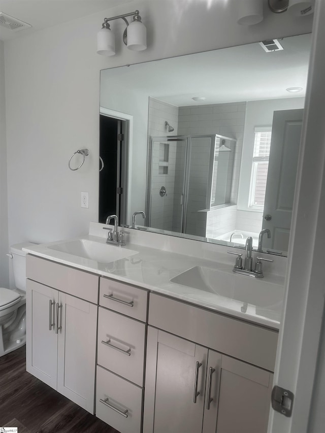 bathroom featuring hardwood / wood-style floors, a shower with door, toilet, and vanity