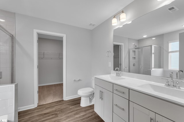 full bath with wood finished floors, visible vents, a sink, and a shower stall