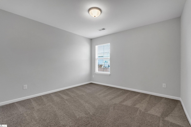 unfurnished room featuring baseboards, dark colored carpet, and visible vents