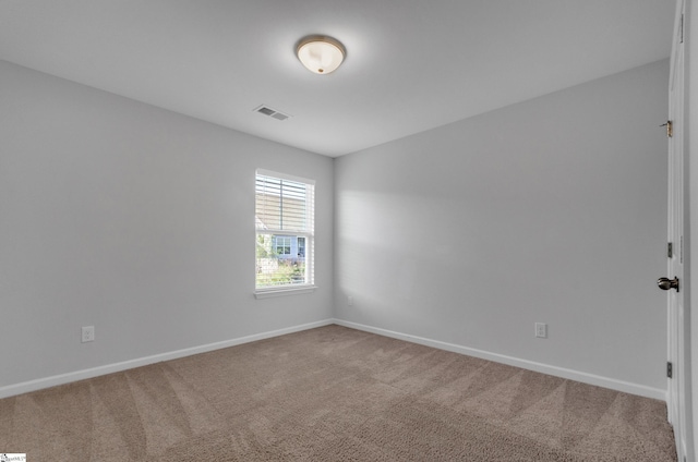 spare room with carpet floors, visible vents, and baseboards