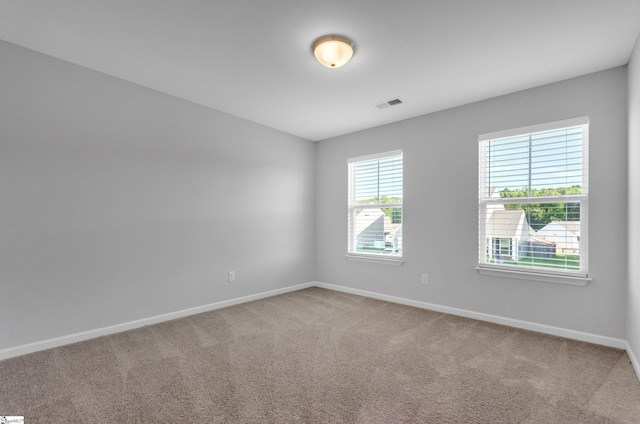 empty room with carpet, visible vents, and baseboards