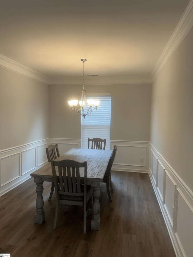 dining space featuring dark wood-type flooring, ornamental molding, and a chandelier