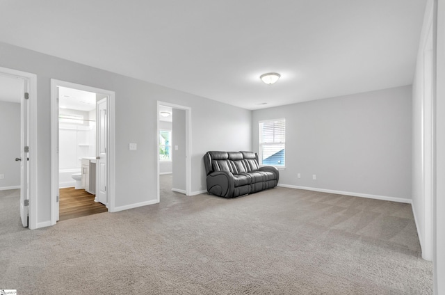living area with baseboards, a healthy amount of sunlight, and carpet