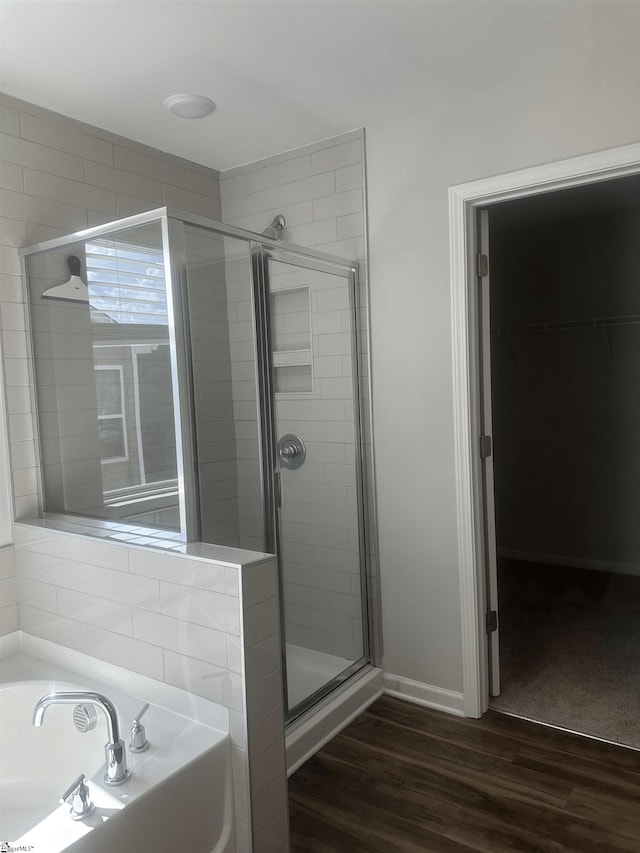 bathroom with hardwood / wood-style flooring and shower with separate bathtub