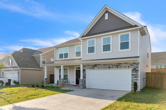 craftsman-style home featuring stone siding, driveway, fence, and covered porch