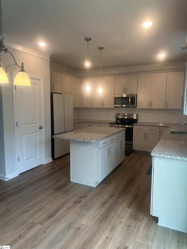 kitchen with hardwood / wood-style floors, sink, appliances with stainless steel finishes, decorative backsplash, and light stone countertops